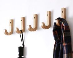 the coat rack is made from wood and has three hooks on one side, two coats hang on the other