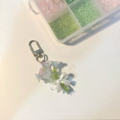 some beads and flowers are sitting on a table next to a container filled with beads