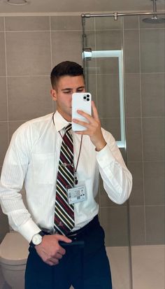 a man taking a selfie with his cell phone in front of him and wearing a tie