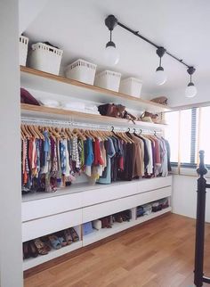 an organized closet with lots of clothes and baskets on the shelves in front of it