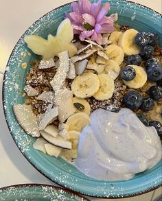 a blue bowl filled with fruit and yogurt on top of a white table