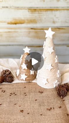 two small white christmas trees sitting on top of a burlock covered table cloth