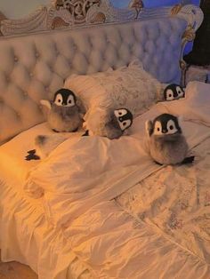 three stuffed penguins sitting on top of a bed