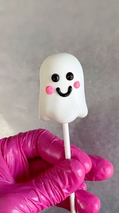 a hand holding a marshmallow with a smiley face on it's stick