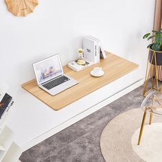 an open laptop computer sitting on top of a wooden desk next to a potted plant