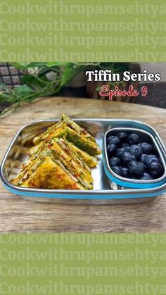 a metal tray filled with food on top of a wooden table next to blueberries