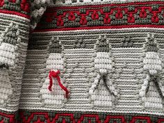 a close up of a knitted sweater with red and white designs on the sleeves