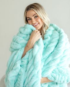 a woman in a blue fur coat posing for the camera with her hands on her chest