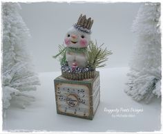 a small snowman sitting on top of a box with music notes and trees in the background