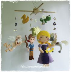 a group of dolls hanging from the ceiling next to a mobile with animals and people on it