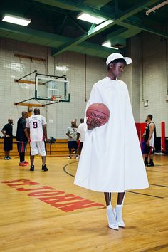 a person in a white cape holding a basketball on a court with other people standing around