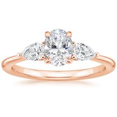 a rose gold engagement ring with three pear shaped diamonds on the band and an accent diamond in the center