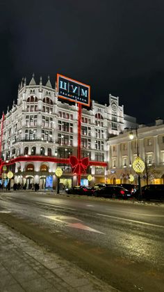 a large white building with many lights on it's sides and cars parked in front