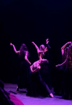 three women are performing on stage with their arms in the air and one woman is holding her leg up