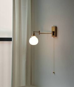 a wall light that is on the side of a white wall next to a window