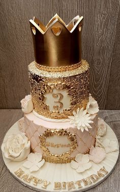 a three tiered cake with gold and white decorations