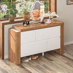 a dresser with a mirror and shoes on it in front of a window, next to a potted plant