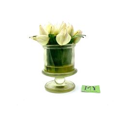 a glass vase filled with white flowers sitting on top of a table next to a sticker