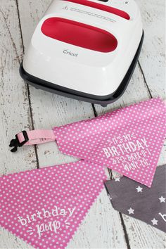 a pink and white birthday bunting banner sitting on top of a wooden floor next to an ironing board