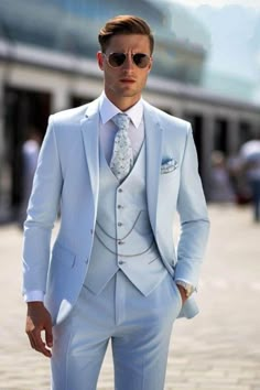 a man in a white suit and sunglasses is standing on the street with his hands in his pockets