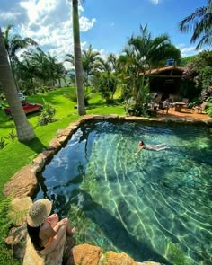 a person laying on the edge of a swimming pool with palm trees in the background