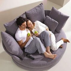 a man and woman sitting on a bean bag chair in the middle of a room