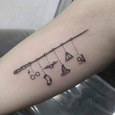 a tattoo on the arm of a woman with an arrow and other items hanging from it