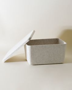 an empty white container sitting on top of a table next to a paper box with a lid