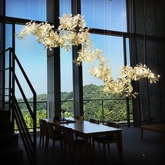 a dining room table with flowers hanging from it's center and stairs leading up to the second floor