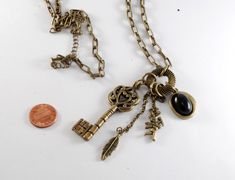 "For sale is a vintage skeleton key necklace. This necklace is brass with a skeleton key, feather, cupid, and a black cabochon. The chain measures 30\". The skeleton key pendant measures 2 1/4\". This is a gorgeous vintage fashion steampunk necklace that will look great with almost any outfit! New treasures added all the time. Check back often!" Vintage Brass Necklaces With Two Keys, Vintage Metal Jewelry With Keys Detail, Vintage Metal Jewelry With Keys, Vintage Metal Key Jewelry, Bronze Brass Necklace With Keys, Vintage Metal Jewelry With Two Keys, Vintage Gold Key Necklace, Vintage Gold Necklaces With Keys, The Skeleton Key