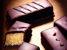 four pieces of chocolate covered cake sitting on top of a brown table next to each other