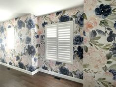 an empty room with floral wallpaper and shutters