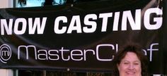 a woman standing in front of a now casting sign