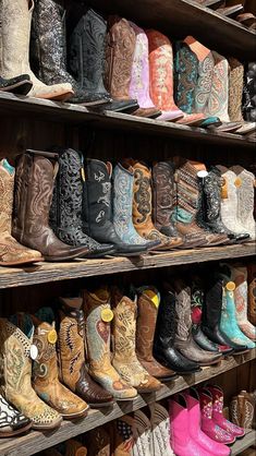 many pairs of cowboy boots are lined up on shelves