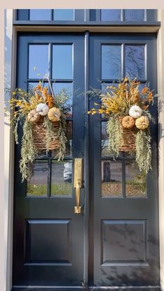 the front door is decorated with two baskets filled with flowers and pumpkins for fall