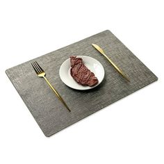 a piece of steak on a plate next to a fork and knife with a place mat