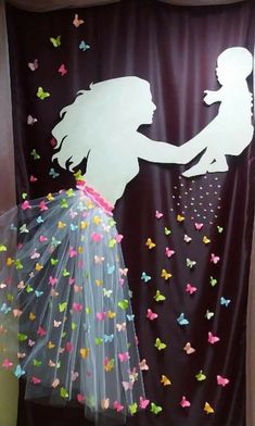 the silhouette of a woman holding a child in front of a curtain with butterflies on it