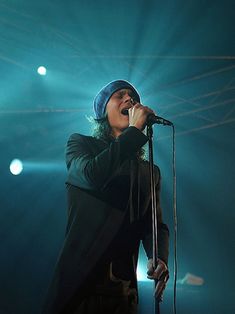 a man singing into a microphone while standing in front of a green stage light at a concert