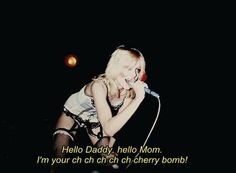 a woman singing into a microphone with an ad in the background that reads hello daddy, hello mom i'm your ch ch ch ch ch ch ch chi cherry bomb