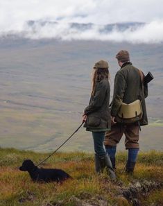 a man and woman walking their dog up a hill