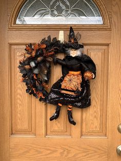 a halloween wreath with a witch doll hanging from it's side on a door