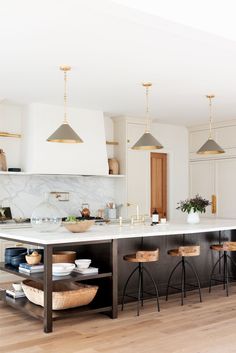 a large kitchen island with stools in front of it and lights hanging from the ceiling