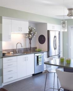 a modern kitchen with white cabinets and stainless steel appliances is pictured in this image from the dining room