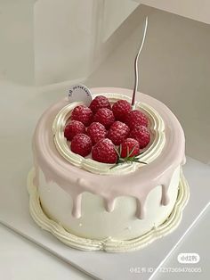 a cake with white icing and raspberries on top