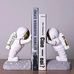 two booksends made to look like astronauts in white suits, one holding the other's hand