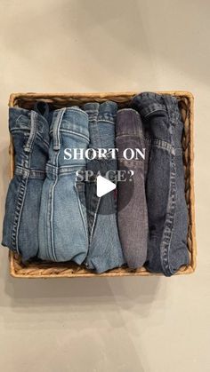 a basket filled with assorted pairs of jeans sitting on top of a white wall