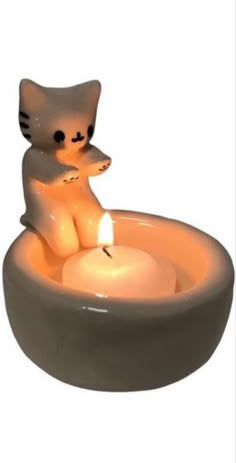 a cat sitting in a bowl with a lit candle