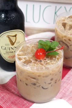 two glasses filled with ice cream and topped with a cherry on the side next to a bottle of guinness