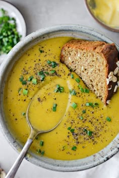 a bowl filled with soup and bread on top of a white table next to other dishes