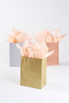 two paper bags with flowers in them on a table